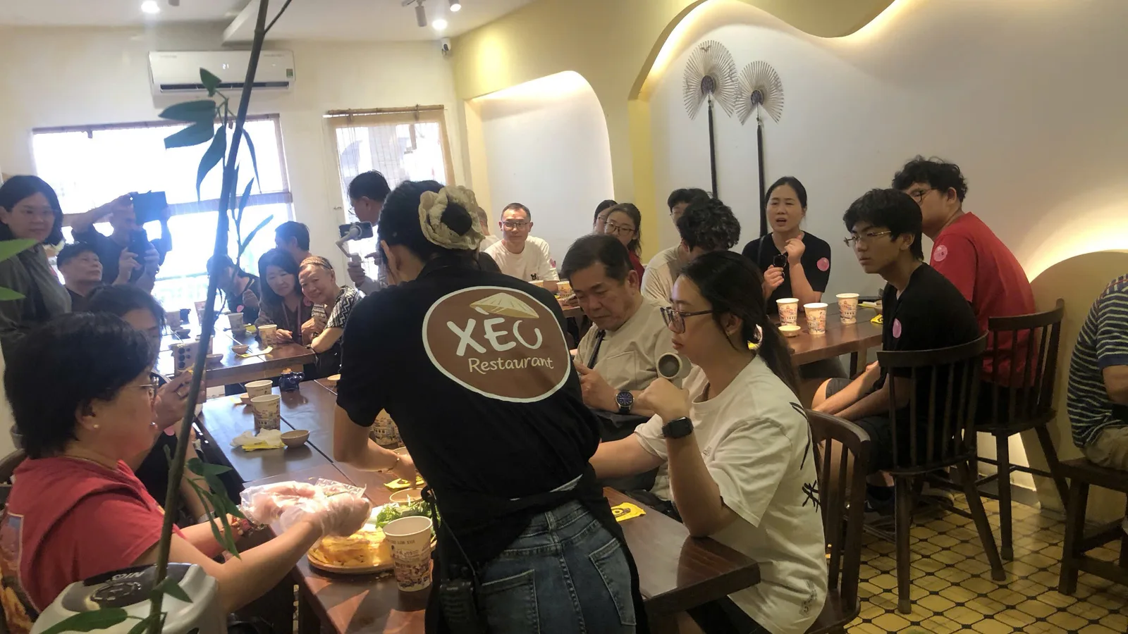 Nhân viên XÈO Restaurant hướng dẫn khách cuộn bánh xèo
